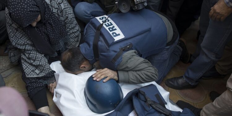 epa11032010 Relatives of Palestinian journalist Samer Abu Daqqa, cameraman for Al Jazeera, who was killed during Israeli air strikes in the southern Gaza Strip, with press crews next to his wrapped body, outside Nasser Hospital in Khan Yunis, southern Gaza Strip, 16 December 2023. More than 18,000 Palestinians and at least 1,200 Israelis have been killed, according to the Palestinian Health Ministry and the Israel Defense Forces (IDF), since Hamas militants launched an attack against Israel from the Gaza Strip on 07 October, and the Israeli operations in Gaza and the West Bank which followed it. EPA-EFE/HAITHAM IMAD